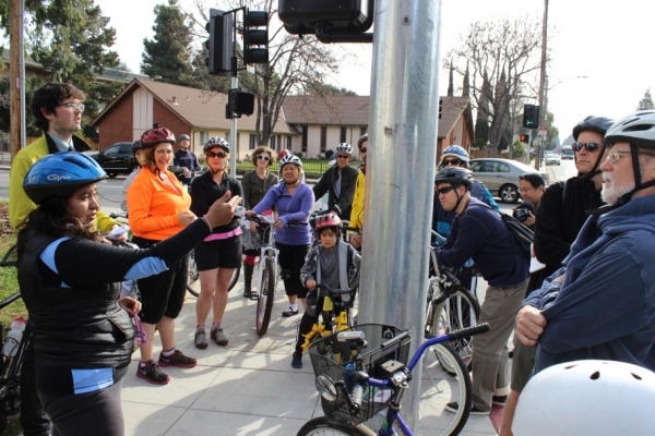 Tour attendes listen to Valeria Craven, left, as she describes the danger crossing the Escuela and California Intersection. Photo By Daniel DeBolt, Mountain View Voice.